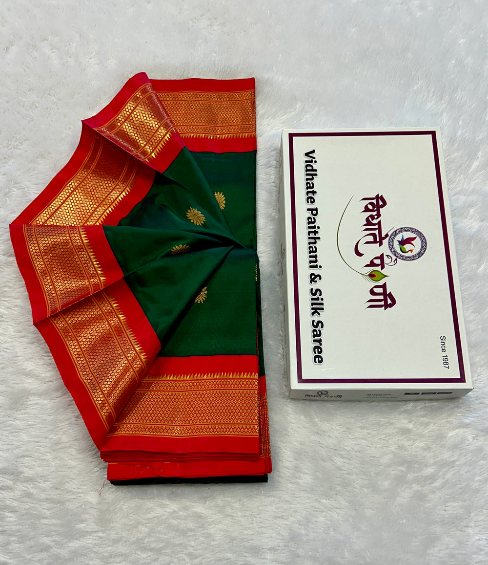 A folded green and red silk saree with gold zari borders is displayed next to its white packaging box on a white textured background. The box is labeled 'Vidhat Pathram & Silk Saree'.