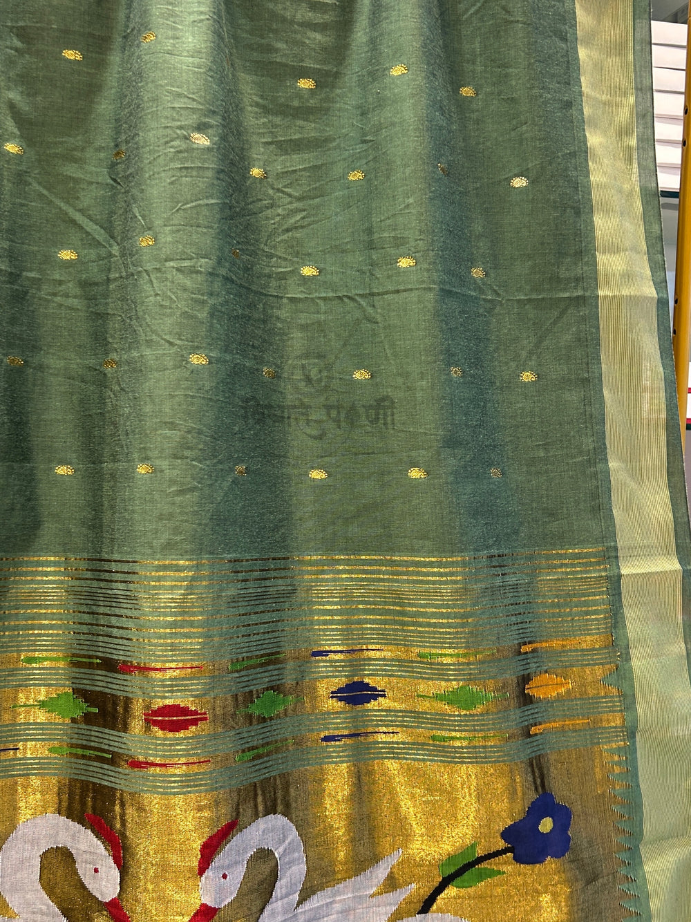 A close-up of a green and gold woven fabric, likely a saree or scarf, featuring a wide gold border, small gold dots, and colorful embroidered motifs including swans and a blue flower.