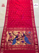 A bright pink silk saree with a wide gold zari border, decorated with two blue peacocks and floral motifs on the pallu.