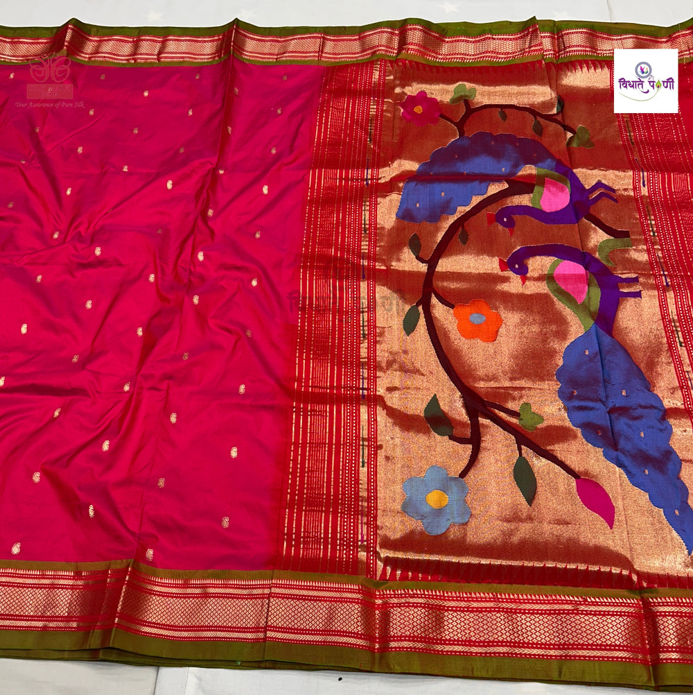 A pink and red silk saree with a wide gold and green border, featuring a detailed peacock and floral motif in blue, purple, orange, and green on the pallu.