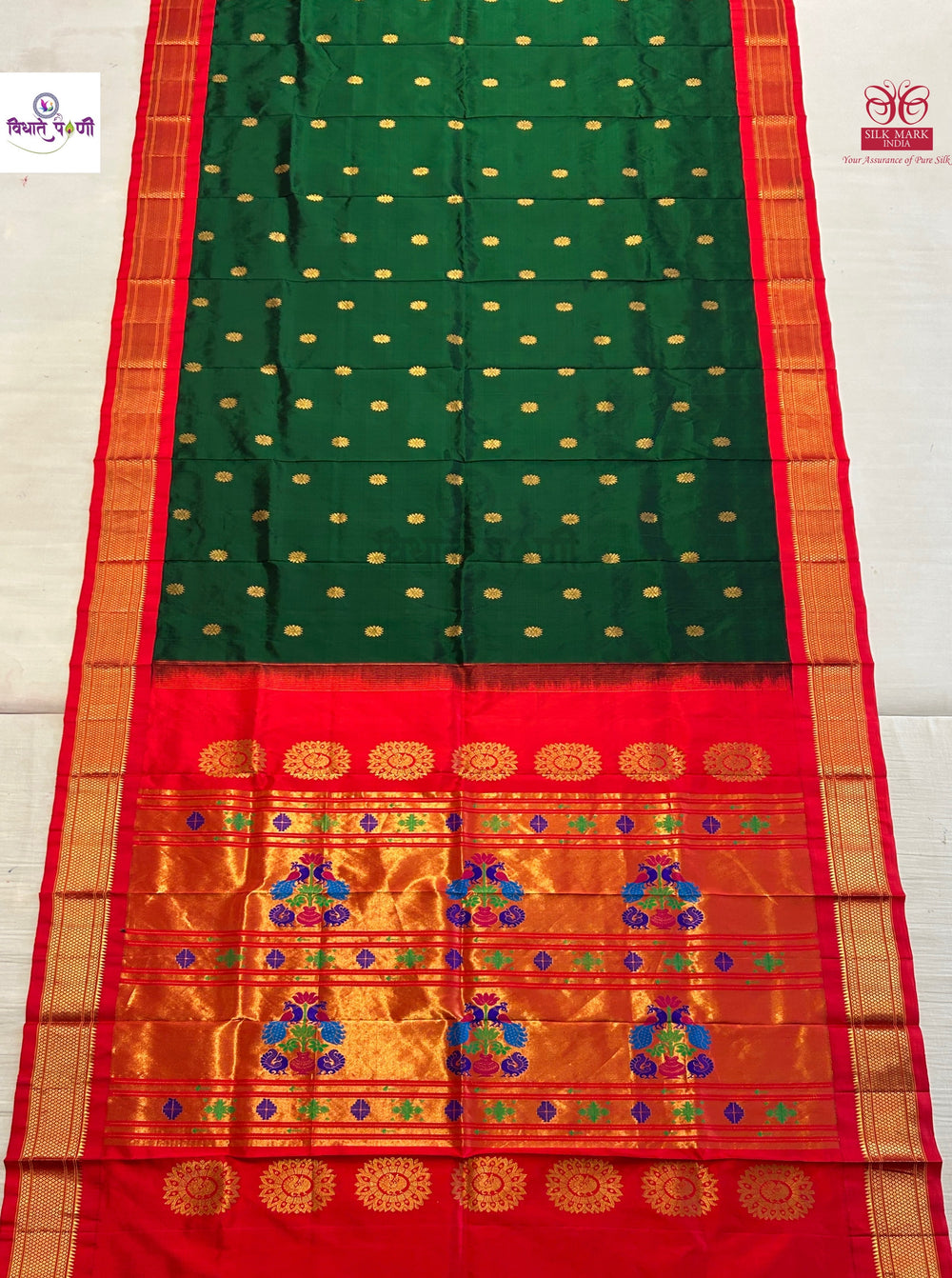 A green and red silk saree with gold zari detailing, featuring a green body with small gold dots, a red border, and a wide golden pallu with intricate floral motifs.