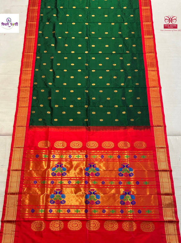 A green and red silk saree with gold zari detailing, featuring a green body with small gold dots, a red border, and a wide golden pallu with intricate floral motifs.