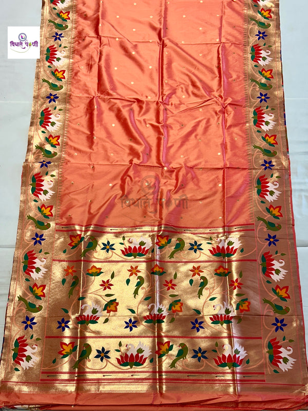 A peach-colored silk saree with a wide gold zari border featuring colorful floral and bird motifs, laid flat on a white surface.