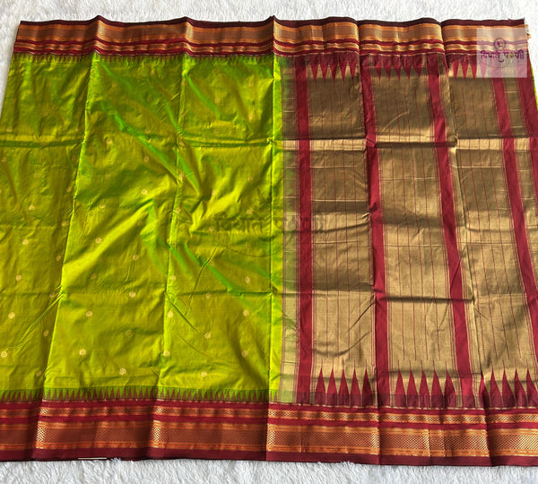 A green and gold silk saree with a red and gold border, laid flat on a white textured background.
