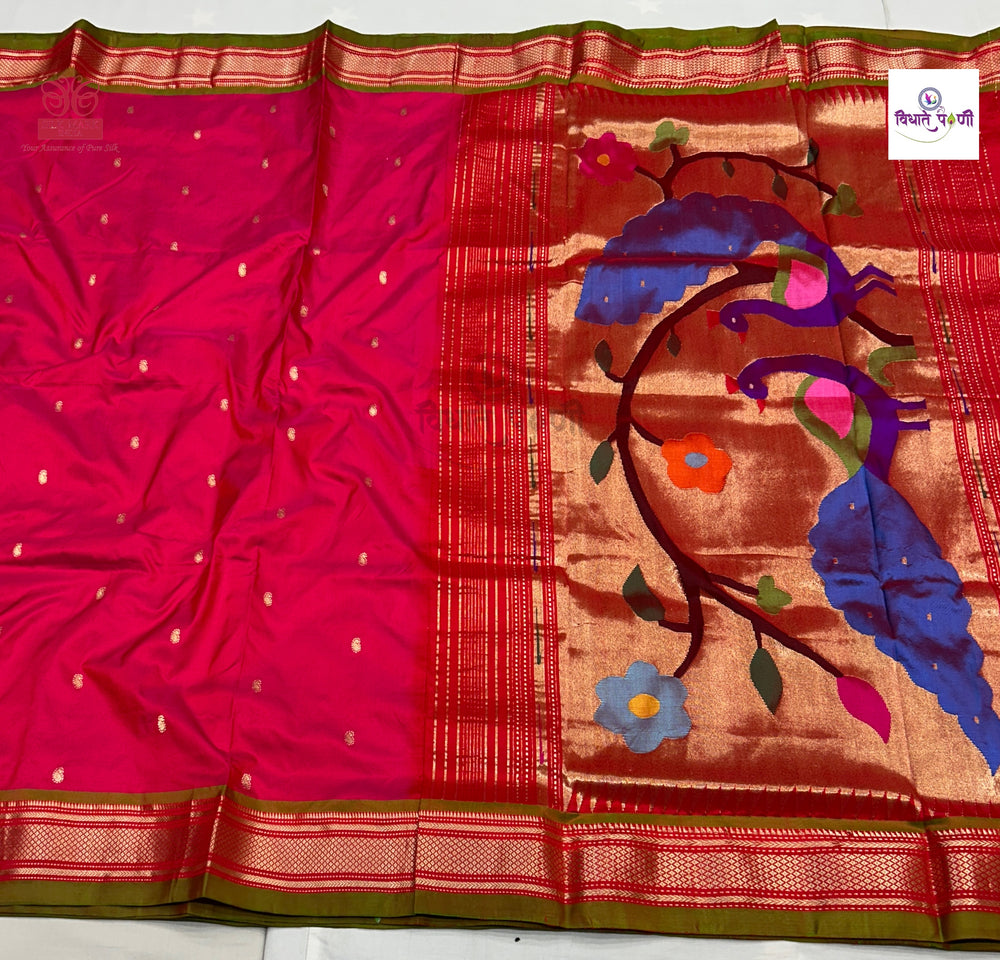 A vibrant magenta pink silk saree with a wide gold and red border, decorated with a large multicolor peacock motif in blue, purple, green, and orange on the pallu.