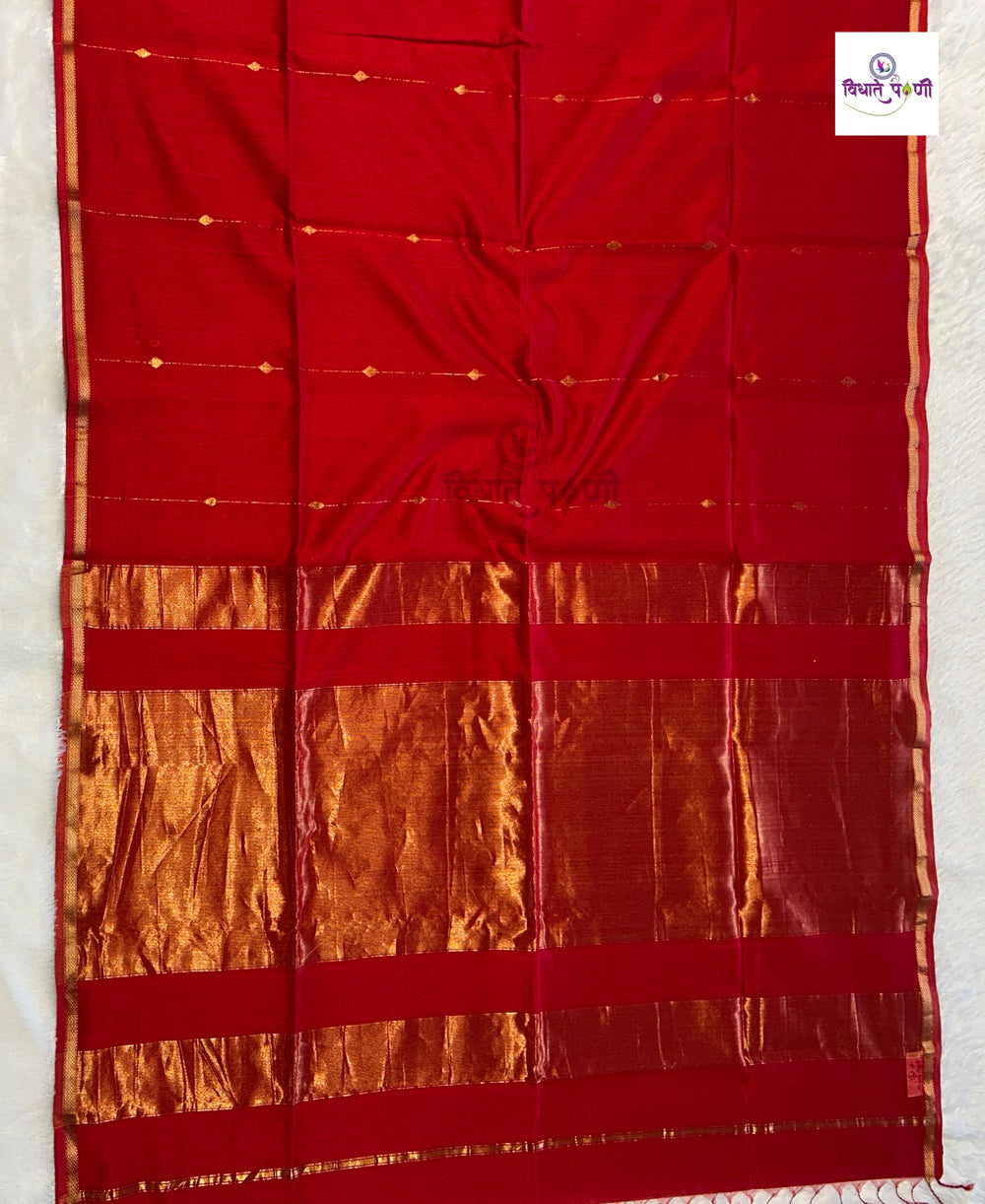 A red silk saree with a wide gold zari border and horizontal metallic gold stripes, laid flat on a white surface.