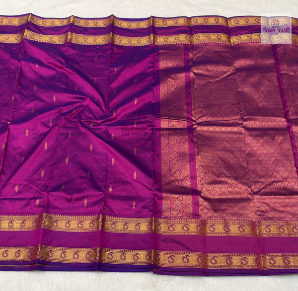 A purple silk saree with gold zari woven borders and motifs, laid flat on a white textured surface.